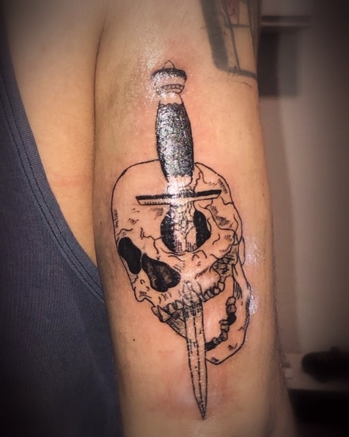 Calavera atravesada por una daga en blackwork en el brazo