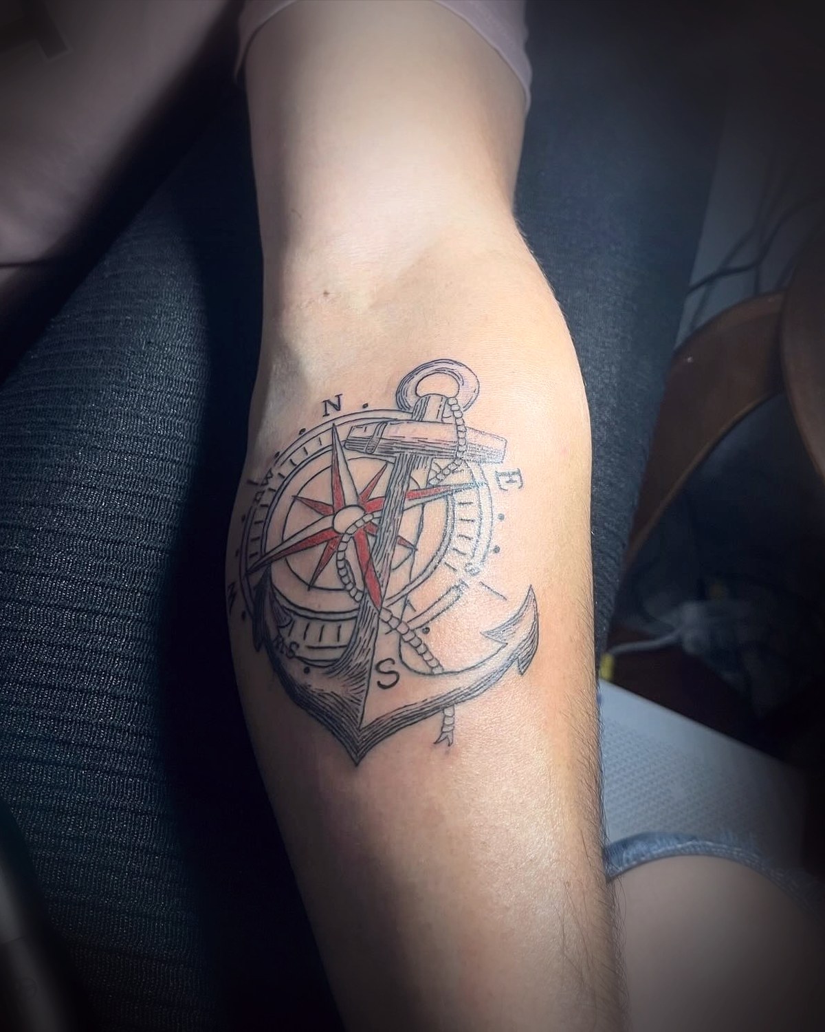 Ancla con rosa de los vientos en línea fina con detalle rojo en el antebrazo