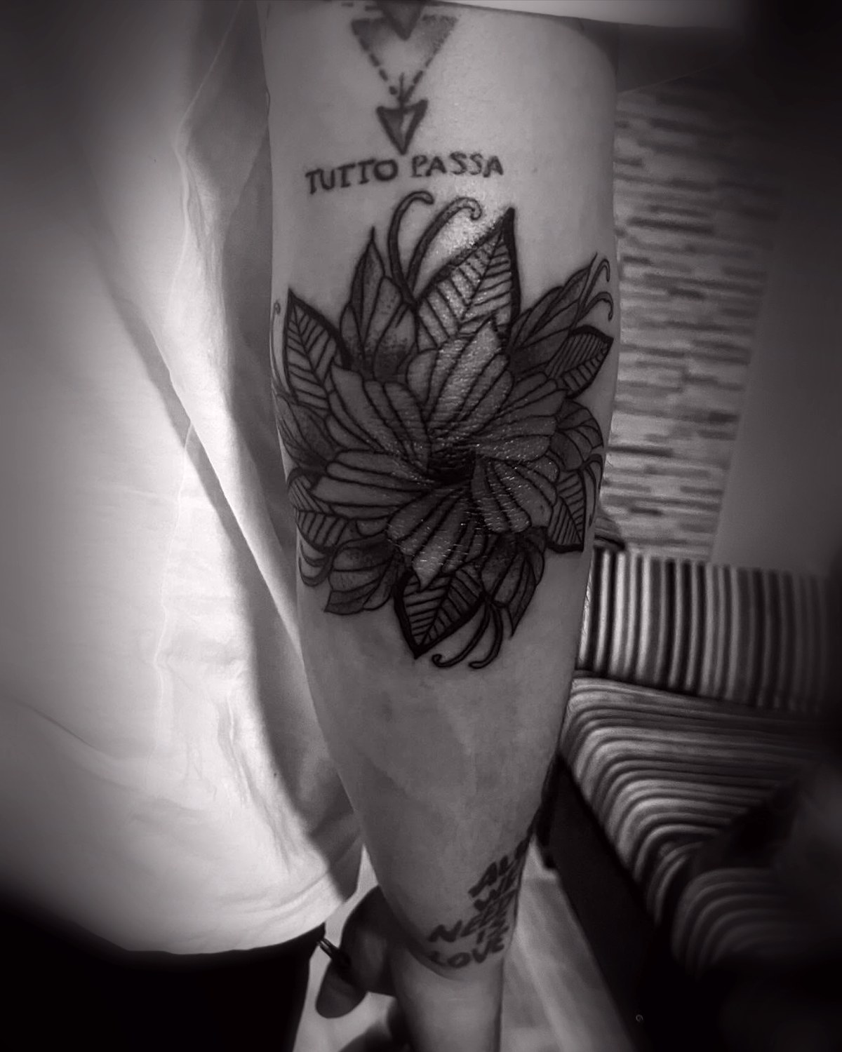 Flor de loto en blackwork con lettering en el brazo