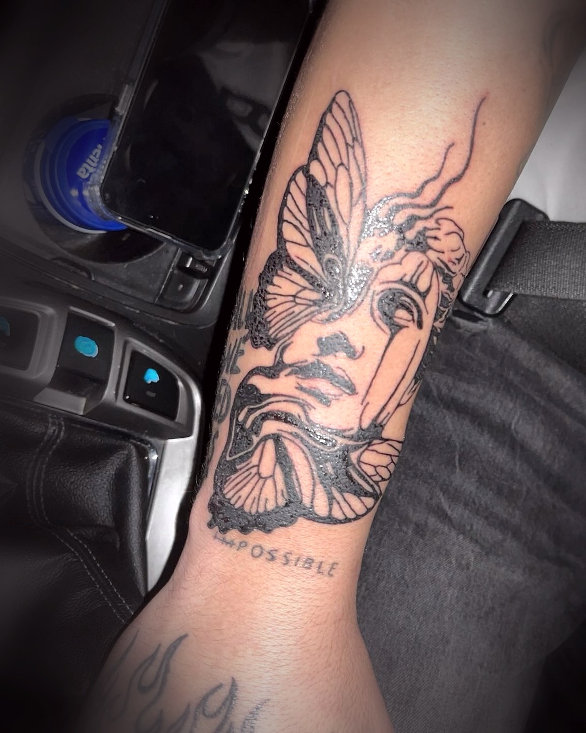 Rostro clásico con mariposas en blackwork en el antebrazo
